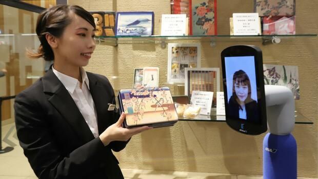 พนักงานในร้าน นำเสนอสินค้าให้ลูกค้าชมผ่านกล้องของหุ่นยนต์ 