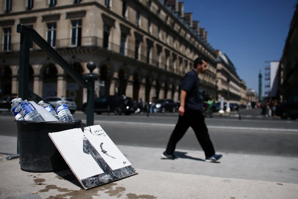 ชายคนหนึ่งเดินผ่านถังบรรจุขวดน้ำที่วางขายใกล้สวนตุยเลอรีในวันที่อากาศอบอุ่นและมีแดดในฤดูใบไม้ผลิที่กรุงปารีส ประเทศฝรั่งเศส วันที่ 19 มิถุนายน 2025