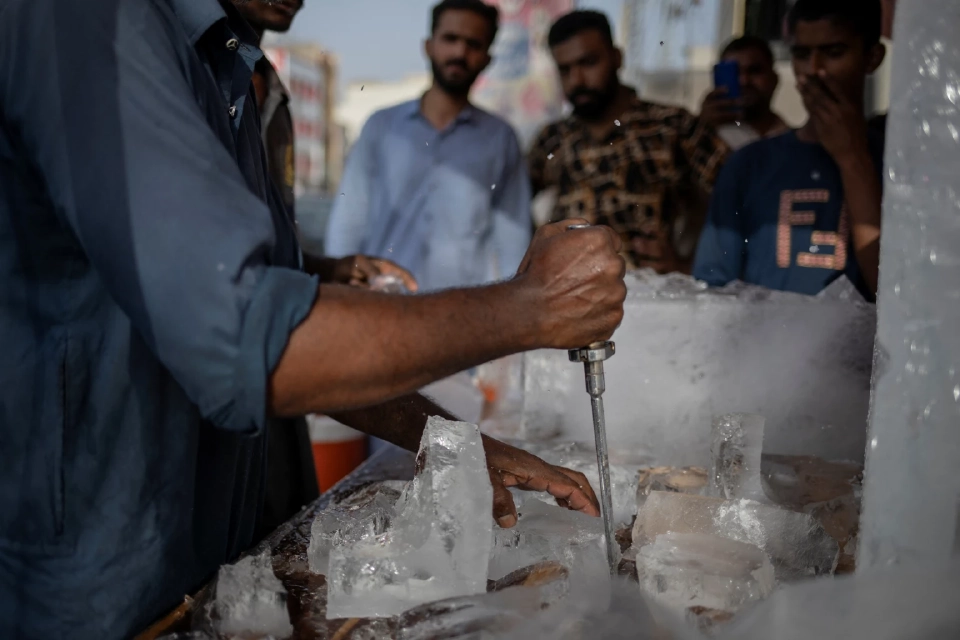 พ่อค้าขายน้ำแข็งกำลังหั่นน้ำแข็งก้อนหนึ่งเพื่อขายในช่วงคลื่นความร้อนในเมืองเซียลโกต ประเทศปากีสถาน เมื่อวันที่ 12 มิถุนายน 2025