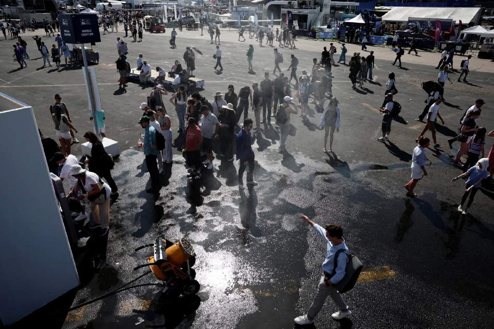 ชายคนหนึ่งกำลังคลายร้อนใต้เครื่องพ่นน้ำในขณะที่นักท่องเที่ยวเข้าคิวเพื่อเติมน้ำในขวดในวันที่อากาศอบอุ่นและมีแดดในงาน Paris Airshow ครั้งที่ 55 ที่สนามบินเลอบูร์เกต์ ใกล้กรุงปารีส ประเทศฝรั่งเศส วันที่ 20 มิถุนายน 2025 REUTERS