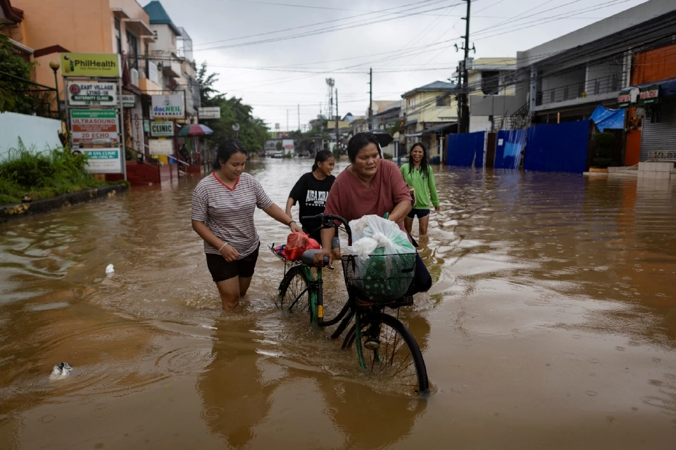 ผู้คนลุยผ่านพื้นที่น้ำท่วมหลังจากฝนตกหนักในฤดูมรสุมที่เมืองเคนตา จังหวัดรีซัล ประเทศฟิลิปปินส์ วันที่ 22 กรกฎาคม 2568 REUTERS