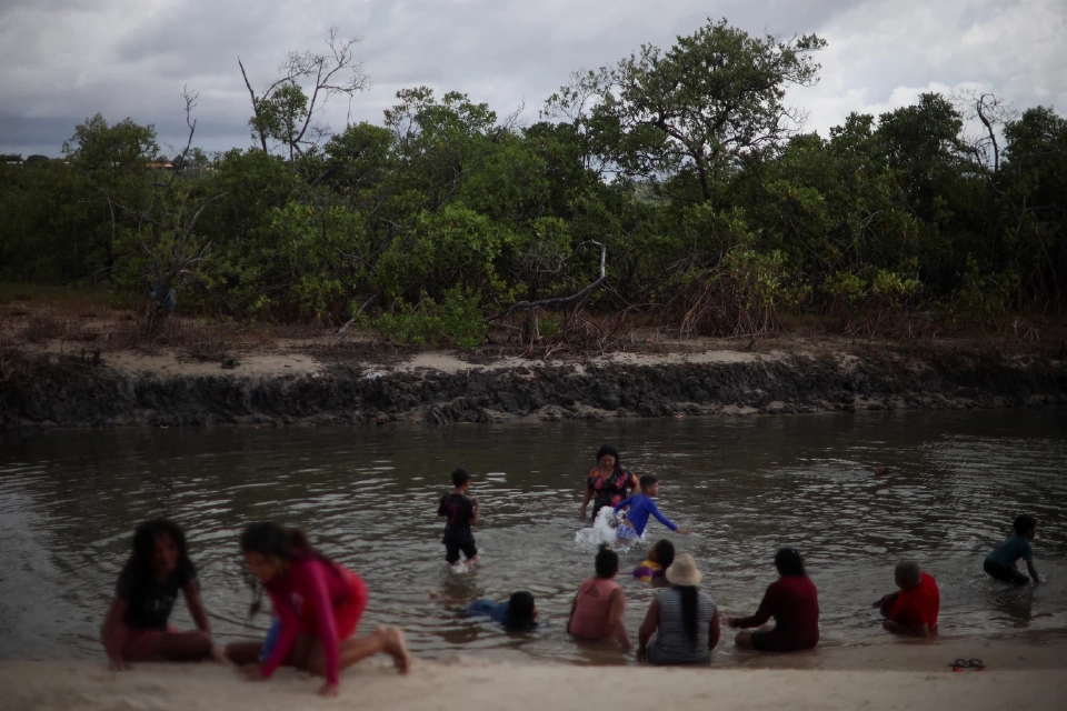 ผู้คนกำลังว่ายน้ำในแม่น้ำสายเล็กๆ ในป่าชายเลนที่เมืองมังเกเซโก ซึ่งเป็นทั้งเครื่องมือสำคัญในการต่อสู้กับการเปลี่ยนแปลงสภาพภูมิอากาศและเป็นเส้นเลือดใหญ่ทางเศรษฐกิจให้กับครอบครัวนับพันที่หาเลี้ยงชีพด้วยการประมง เก็บของป่า ท่องเที่ยวเชิงนิเวศ และเลี้ยงผึ้ง ในเมืองราโปซา รัฐมารันเยา ประเทศบราซิล เมื่อวันที่ 1 พฤษภาคม 2025 ภาพโดย REUTERS