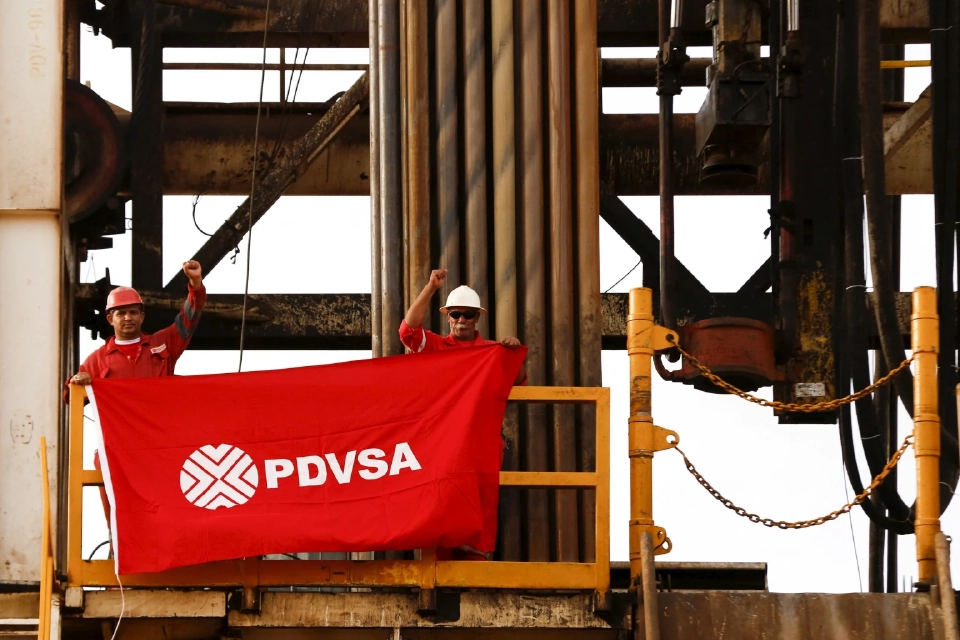 คนงานในบ่อน้ำมันถือธงที่มีโลโก้ของ บริษัทน้ำมันแห่งรัฐ เวเนซุเอลา PDVSA บนแท่นขุดเจาะน้ำมันในบ่อน้ำมันที่บริษัทดำเนินการอยู่ ในเขตน้ำมันโอริโนโกที่อุดมสมบูรณ์ ใกล้กับเมืองคาบรูติกา ในรัฐอันโซอาเตกี เมื่อวันที่ 16 เมษายน 2558 ภาพถ่ายเมื่อวันที่ 16 เมษายน 2558 REUTERS